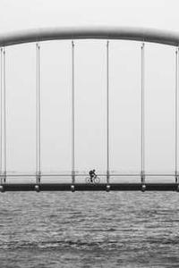 A person rides a bike across a suspension bridge